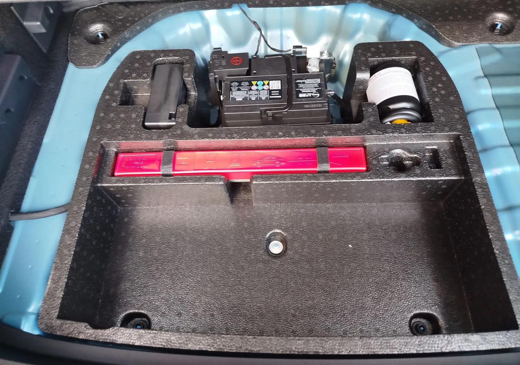 Vue rapprochée du coffre du MG ZS Cosmo Blue 2026, montrant la batterie et le rangement d’outils intégrés.