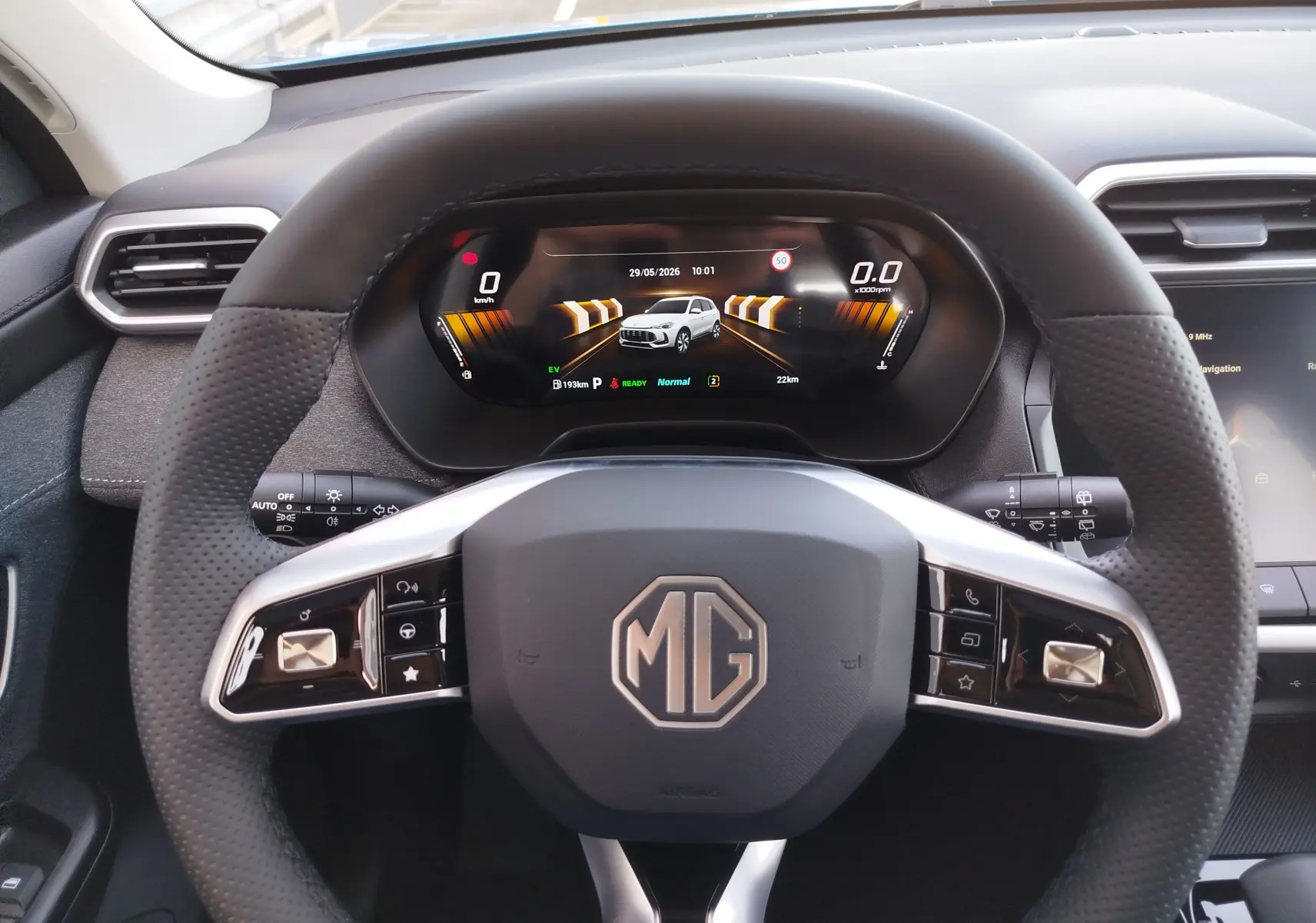 Vue intérieure centrée sur le volant noir perforé MG ZS 2026 avec tableau de bord numérique et écran tactile partiel.
