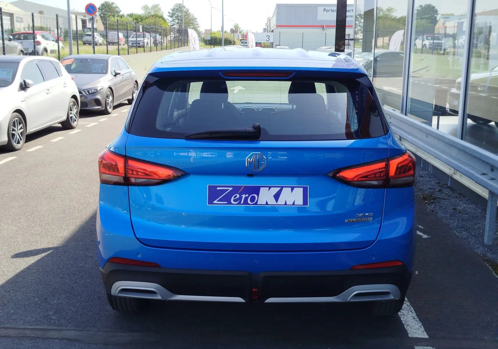 Vue arrière du MG ZS 1.5 L Hybrid+ 197 ch en Cosmo Blue, avec feux LED et plaque Zéro KM visible.