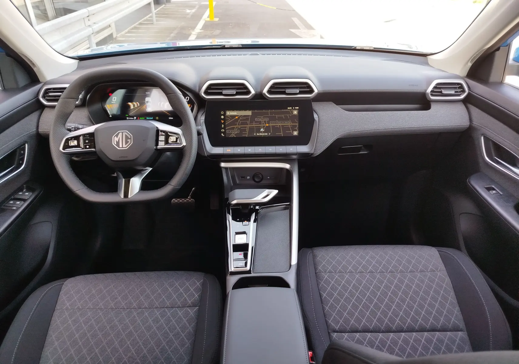 Vue intérieure avant du MG ZS 2026, tableau de bord noir avec écran tactile central et sièges en tissu noir.