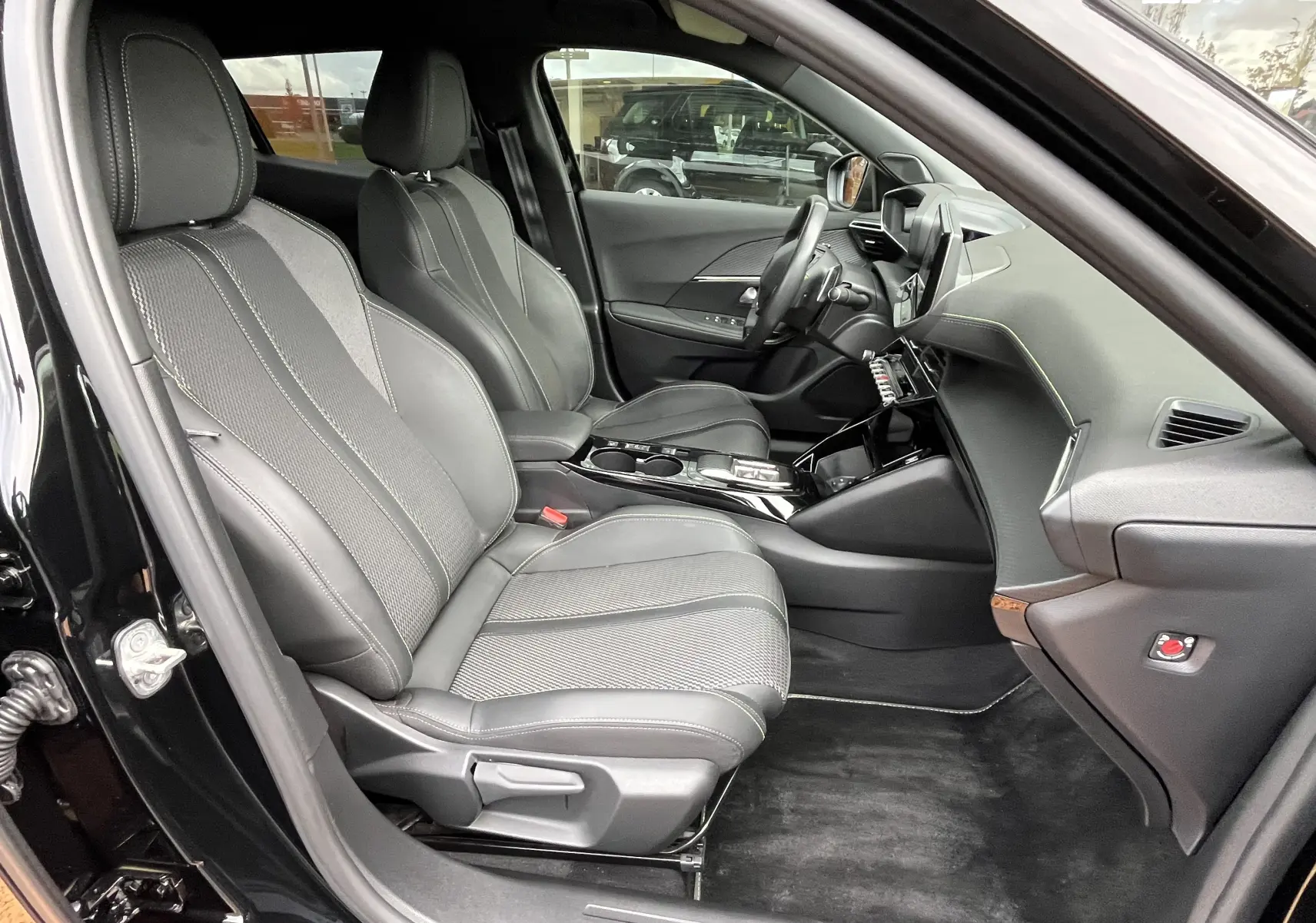 Vue intérieure côté conducteur du Peugeot 2008 GT 2024 noir, sièges en cuir et tissu avec console centrale moderne.