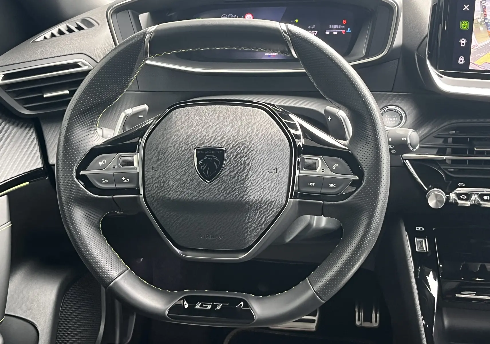 Vue rapprochée du volant noir perforé du Peugeot 2008 GT 2024 avec logo lion et commandes intégrées.