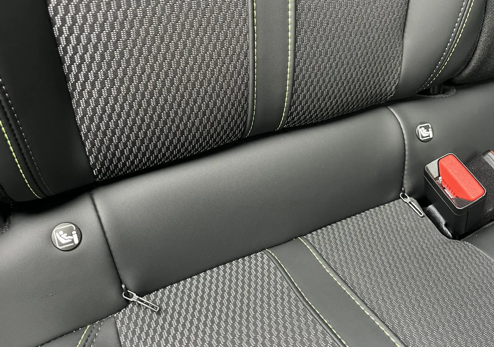 Détail de la banquette arrière noire du Peugeot 2008 2024 avec surpiqûres vertes et attaches ISOFIX visibles.