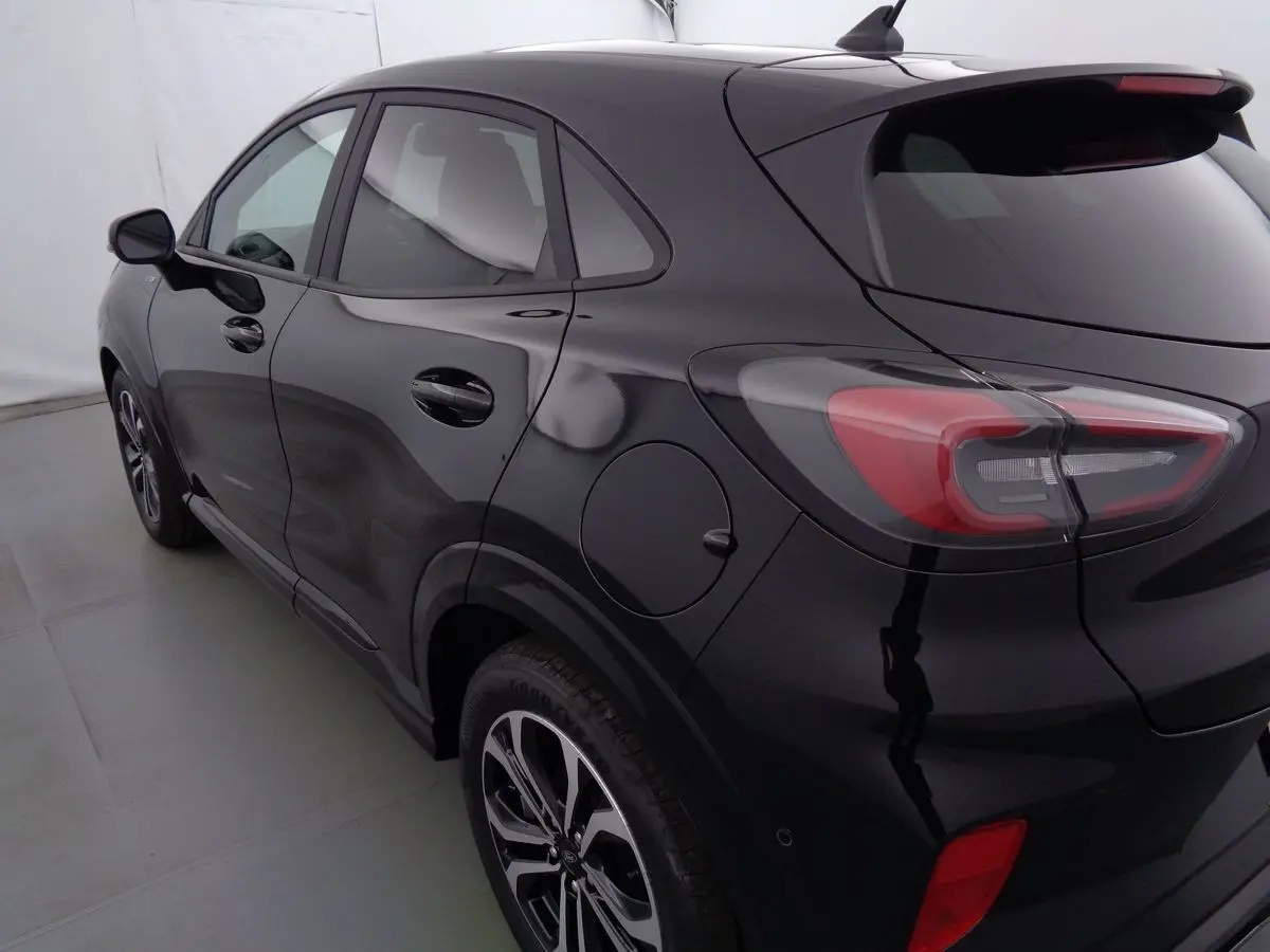 Vue 3/4 arrière côté gauche d'un Ford Puma noir Agate Métal avec jantes alliage bicolores et feux arrière LED distinctifs.