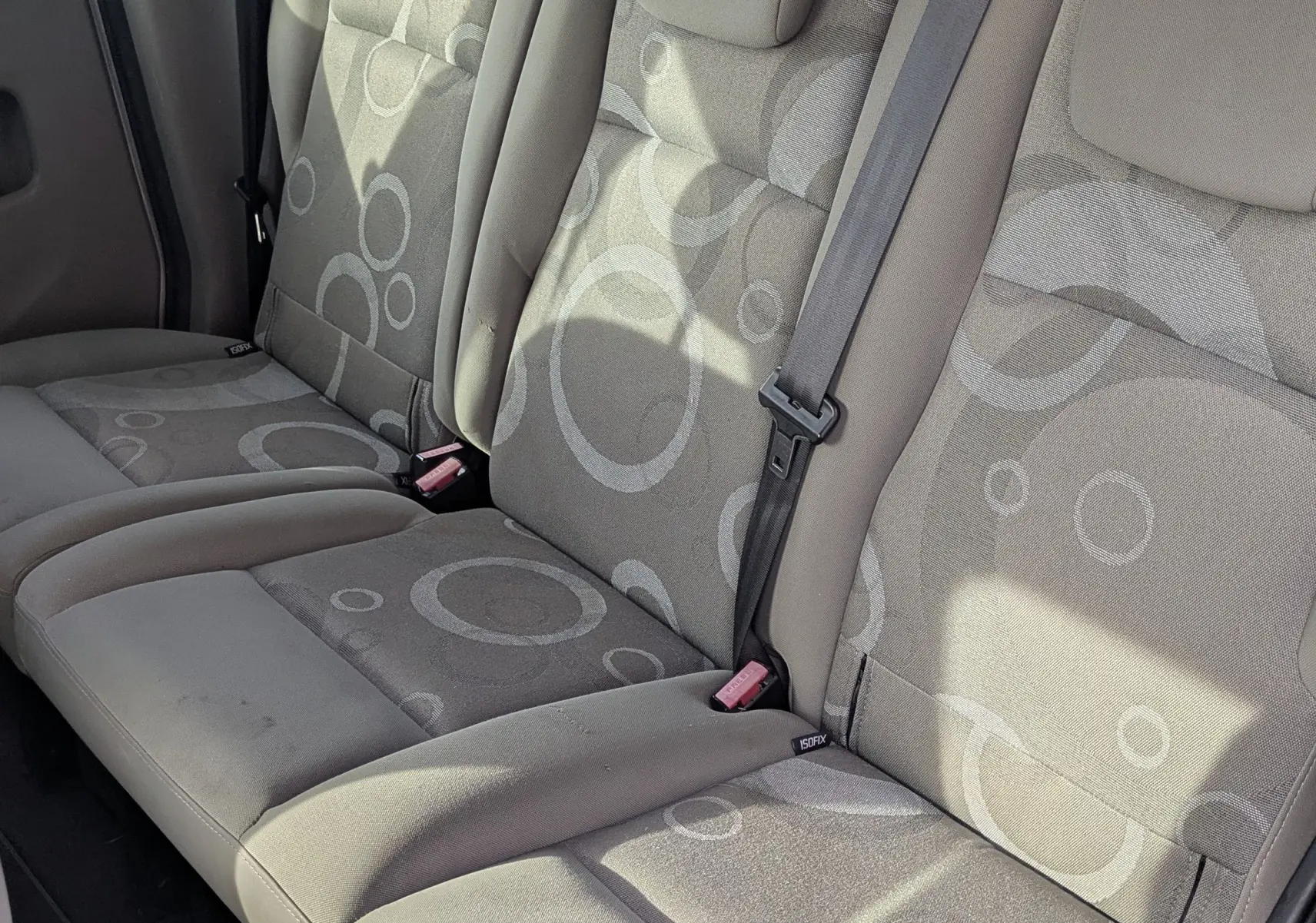 Banquette arrière en tissu gris à motifs ronds dans un Renault Kangoo II bleu ciel, vue côté droit intérieur arrière.
