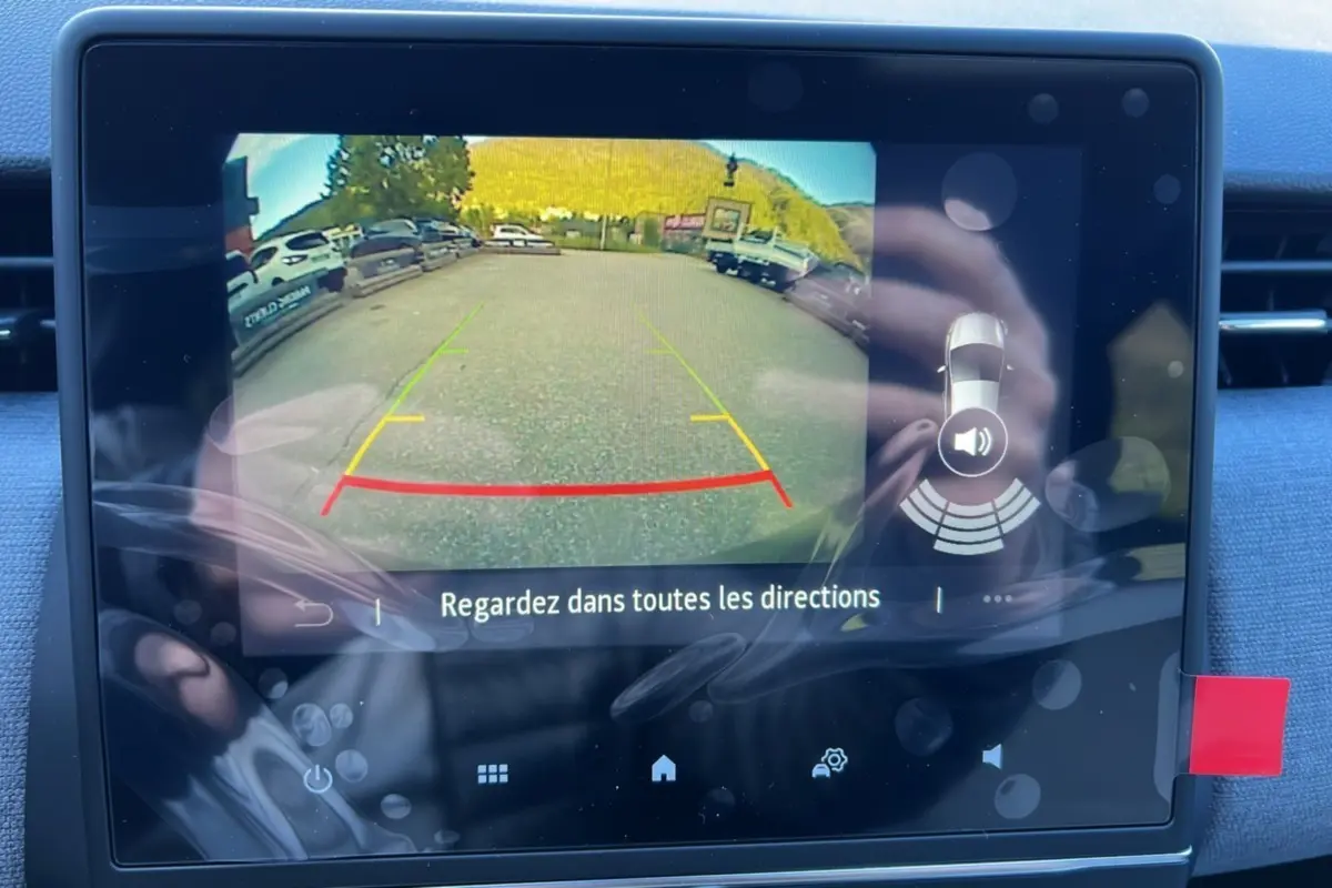 Écran de caméra de recul affichant l'aide au stationnement d'une Renault Clio gris schiste, version DCI 100 Evolution 2025.