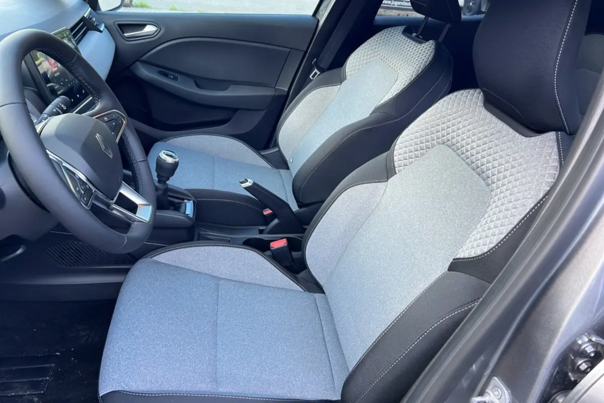 Intérieur de la Renault Clio DCI 100 Evolution Camera 2025, sièges gris clair avec surpiqûres et volant noir visible côté conducteur.