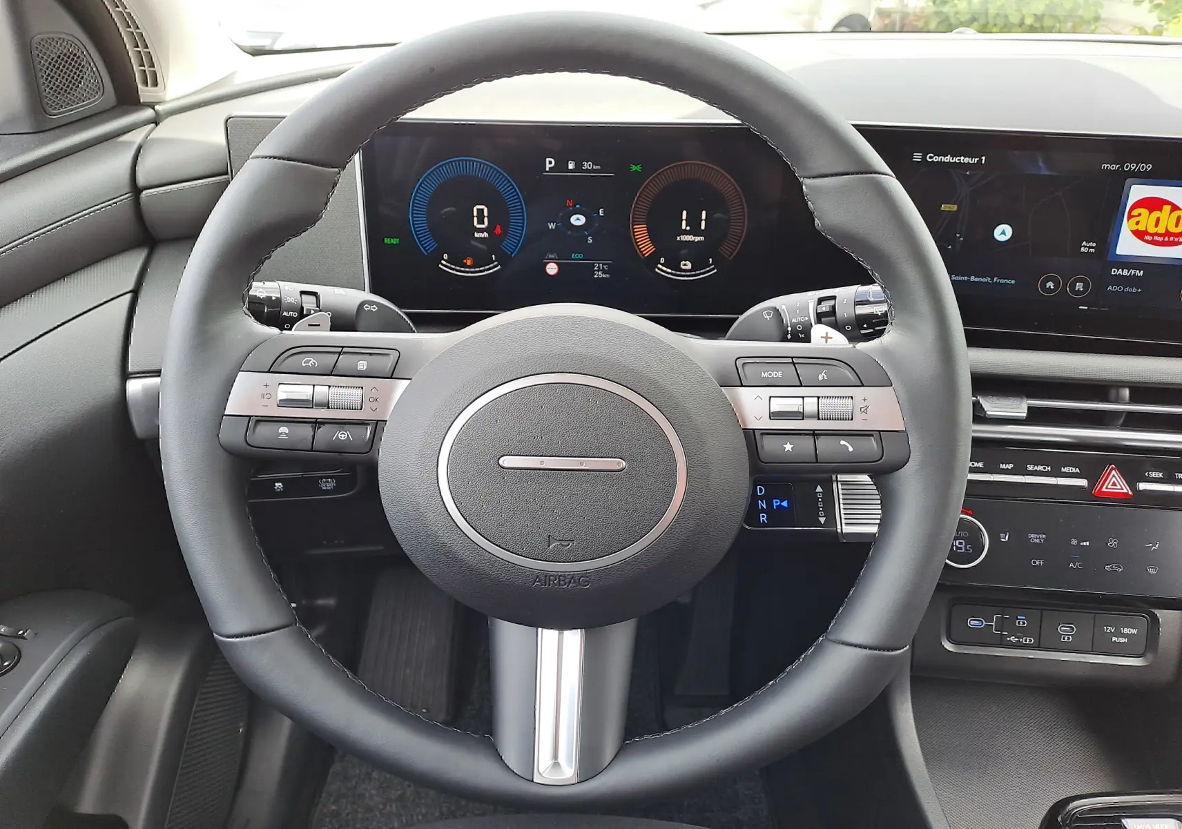 Vue intérieure centrée sur le volant noir et le tableau de bord numérique du Hyundai Tucson 2025 gris Ecotronic.