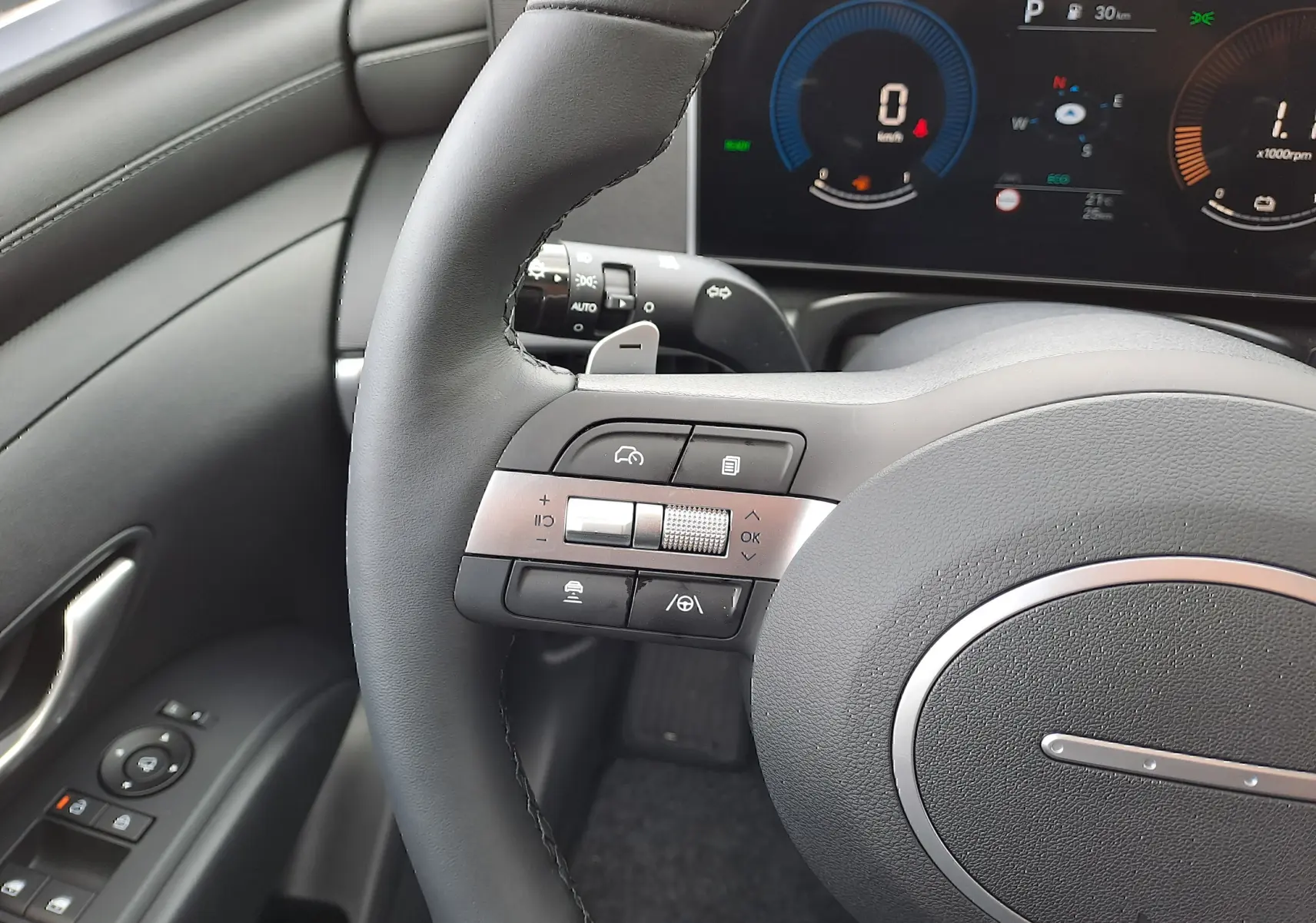 Gros plan sur le volant noir et les commandes multifonctions du Hyundai Tucson 2025 avec tableau de bord numérique en arrière-plan.