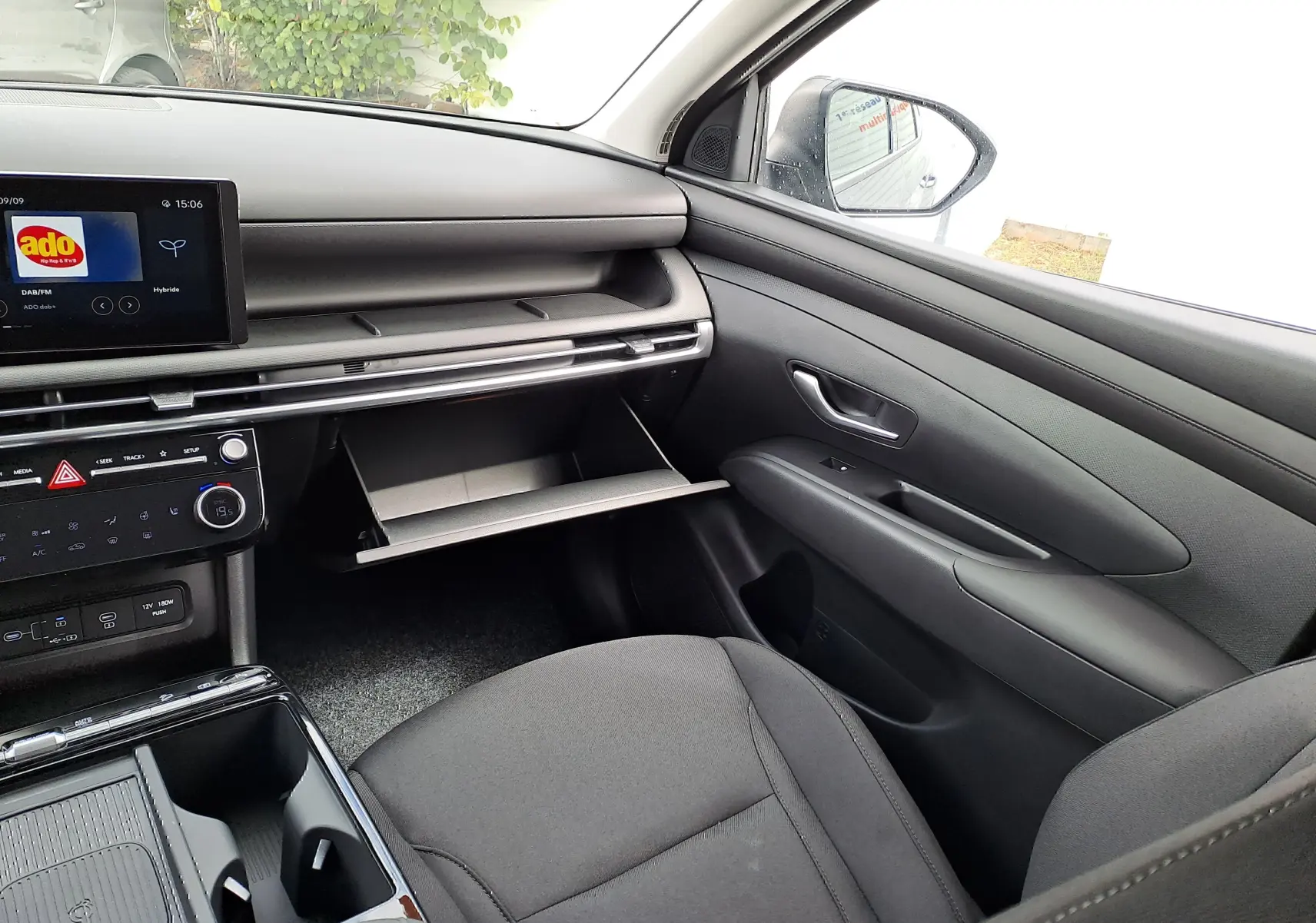 Intérieur côté passager du Hyundai Tucson 2025 gris Ecotronic, avec boîte à gants ouverte et tableau de bord moderne noir.