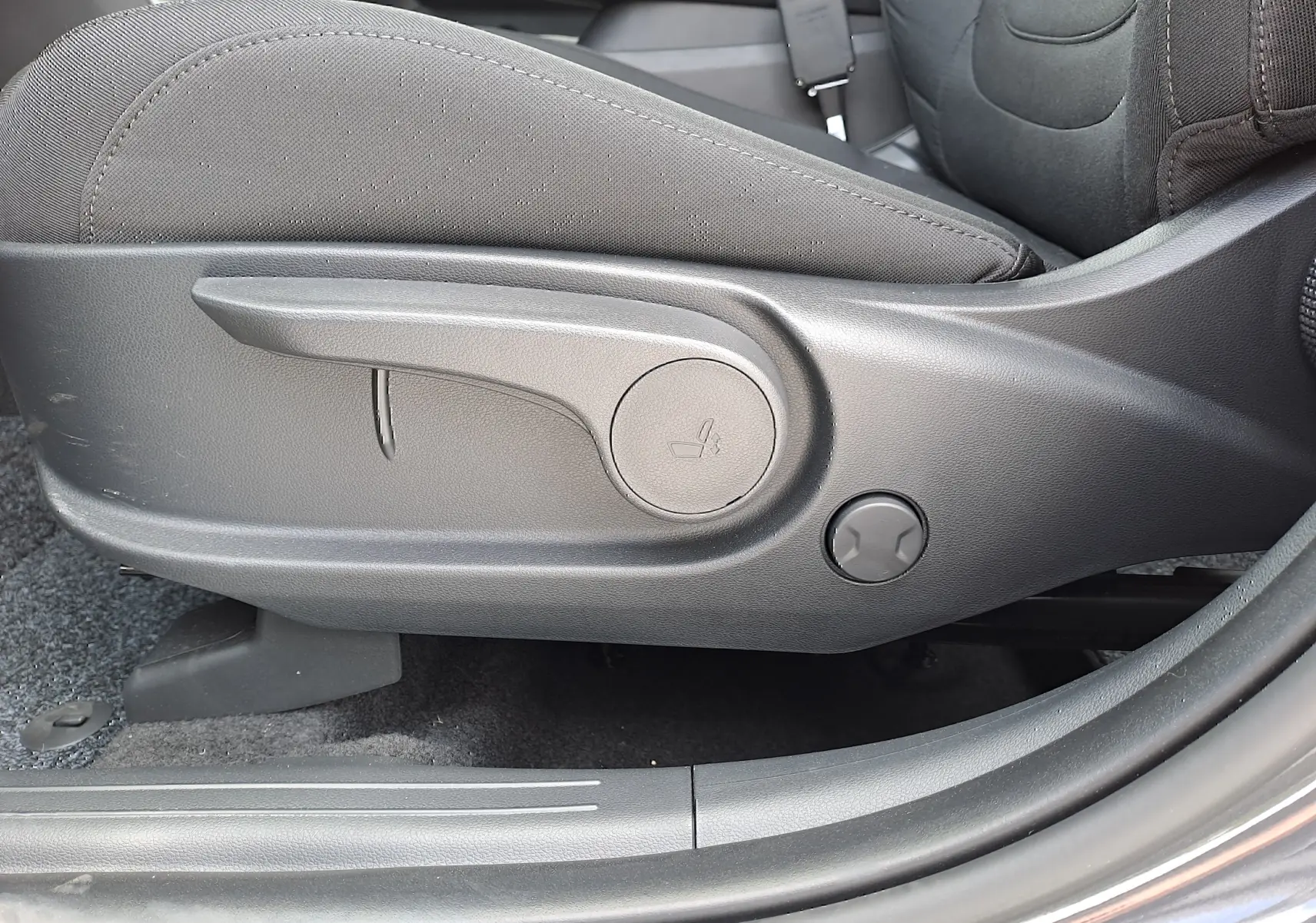 Gros plan sur le côté gauche du siège avant tissu noir du Hyundai Tucson 2025, montrant les commandes de réglage manuel.