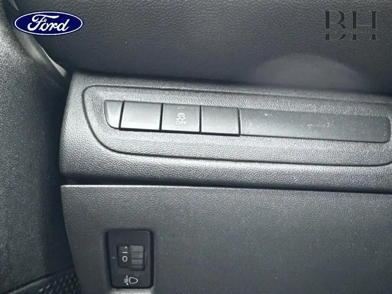 Gros plan sur les commandes de tableau de bord noir d'une Peugeot 208 blanche, avec bouton de désactivation de l'ESP visible.