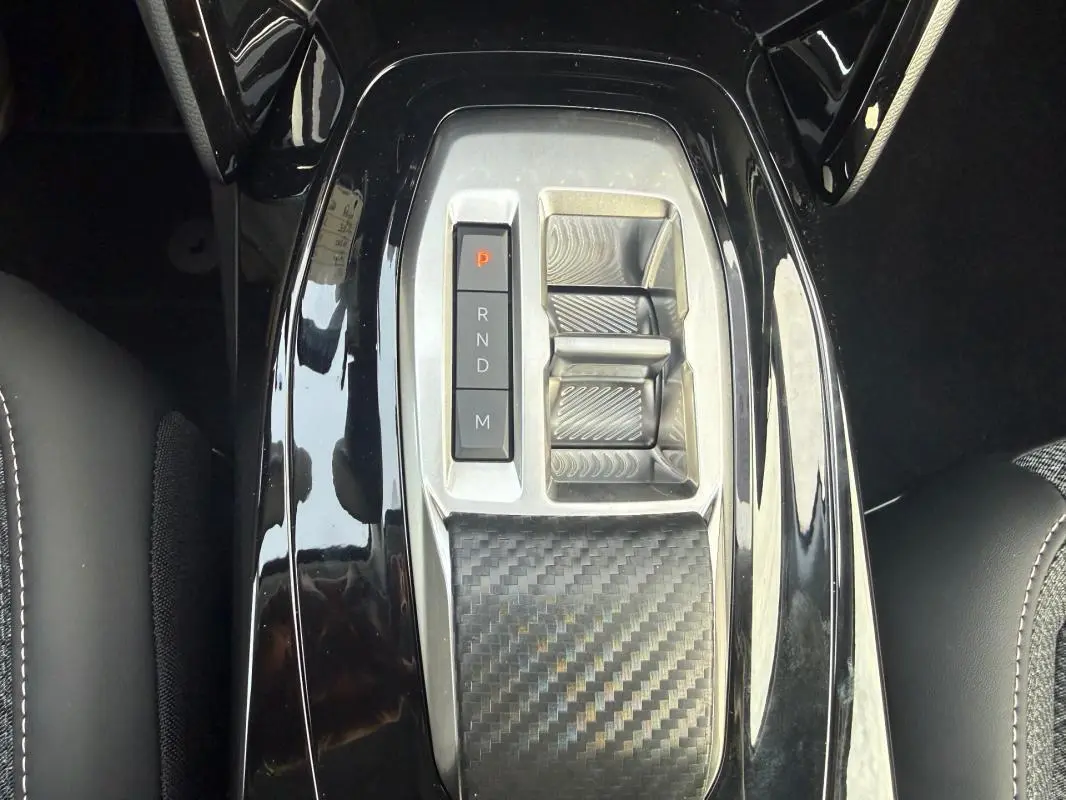 Gros plan sur la console centrale noire brillante de la Peugeot 208 Hybrid 110 e-DCS6 Allure avec sélecteur de boîte auto.