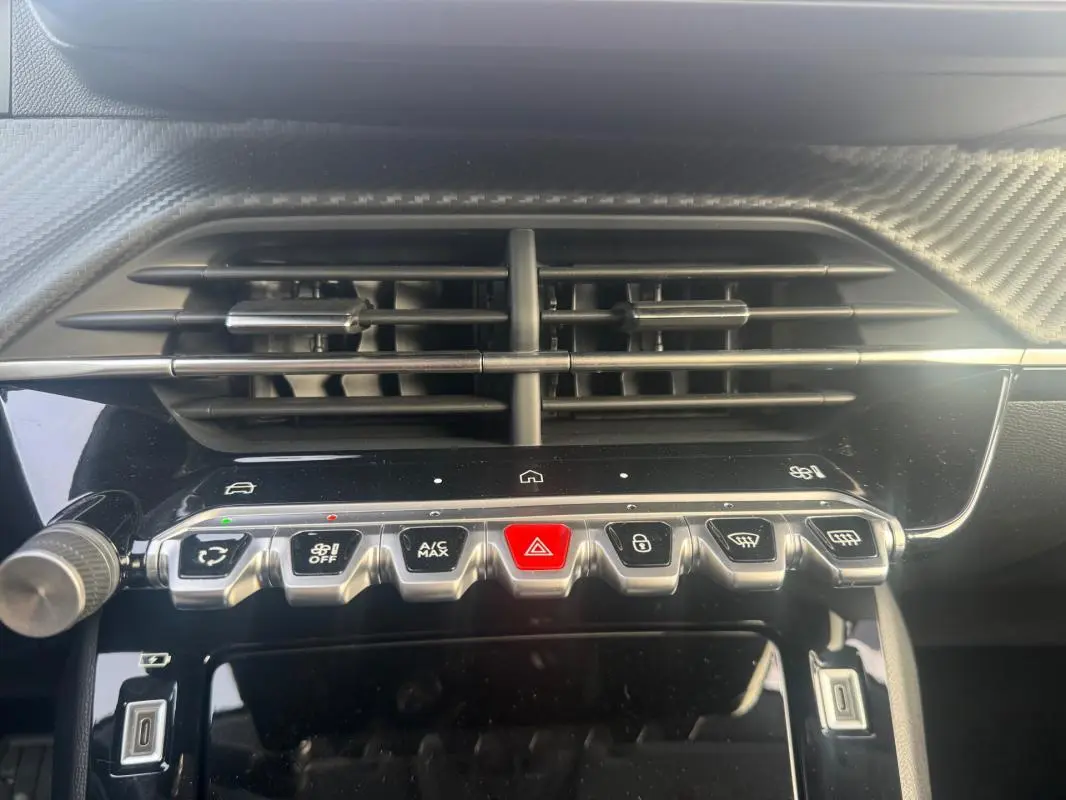 Vue rapprochée du tableau de bord de la Peugeot 208 gris, mettant en valeur les commandes centrales et les aérateurs.