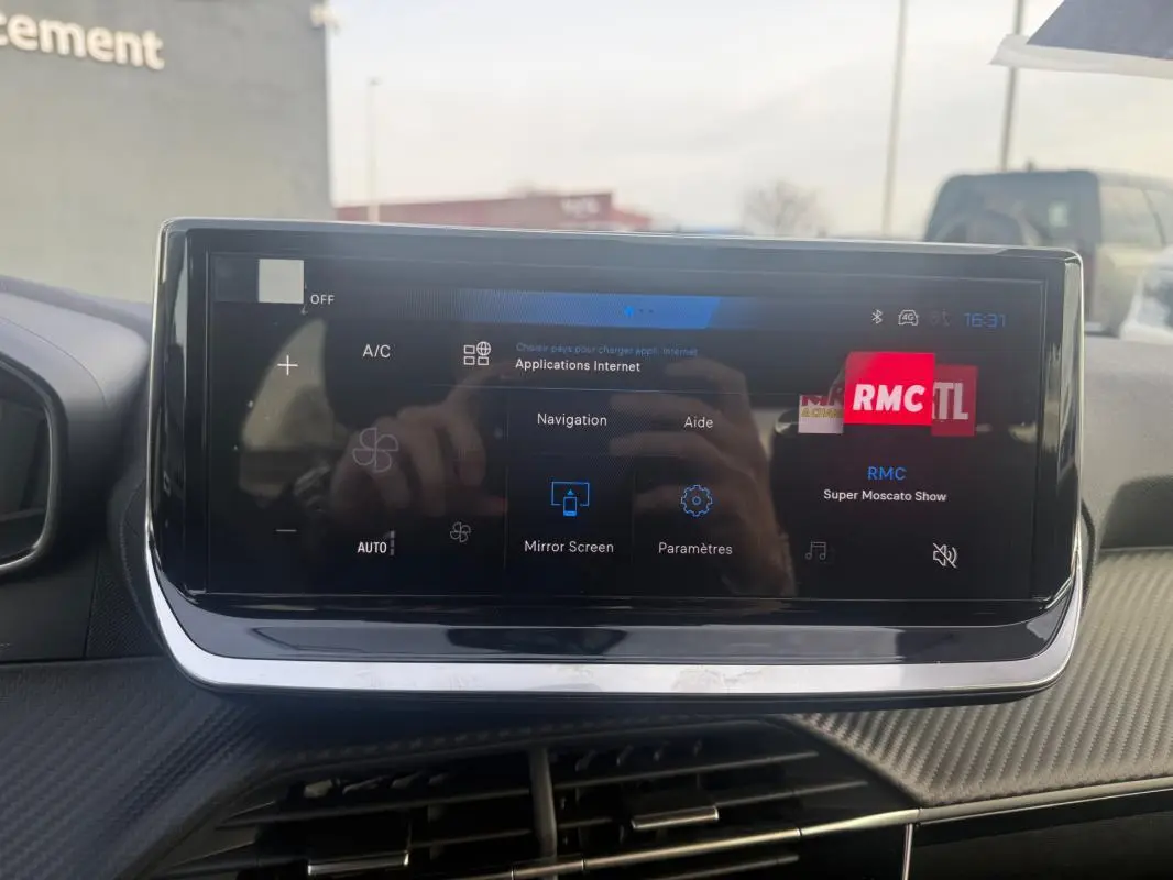 Écran tactile du tableau de bord de la Peugeot 208 Hybrid gris, affichant les options de navigation et radio RMC.
