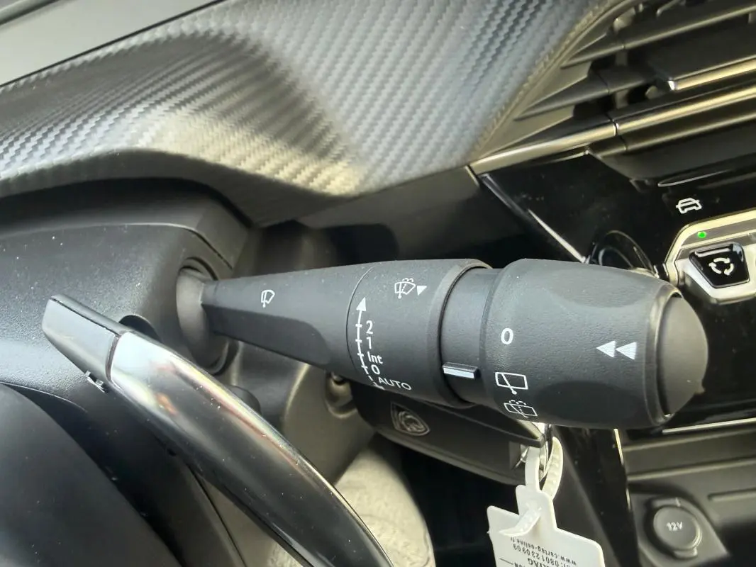 Gros plan sur la commande des essuie-glaces dans l’habitacle gris de la Peugeot 208 Hybrid 110 e-DCS6 Allure 2025.