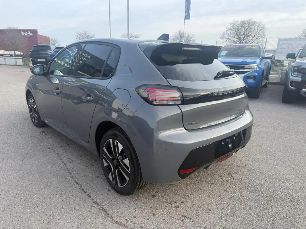 Vue 3/4 arrière droite d'une Peugeot 208 gris métallisé avec jantes alliage et antenne requin sur toit.