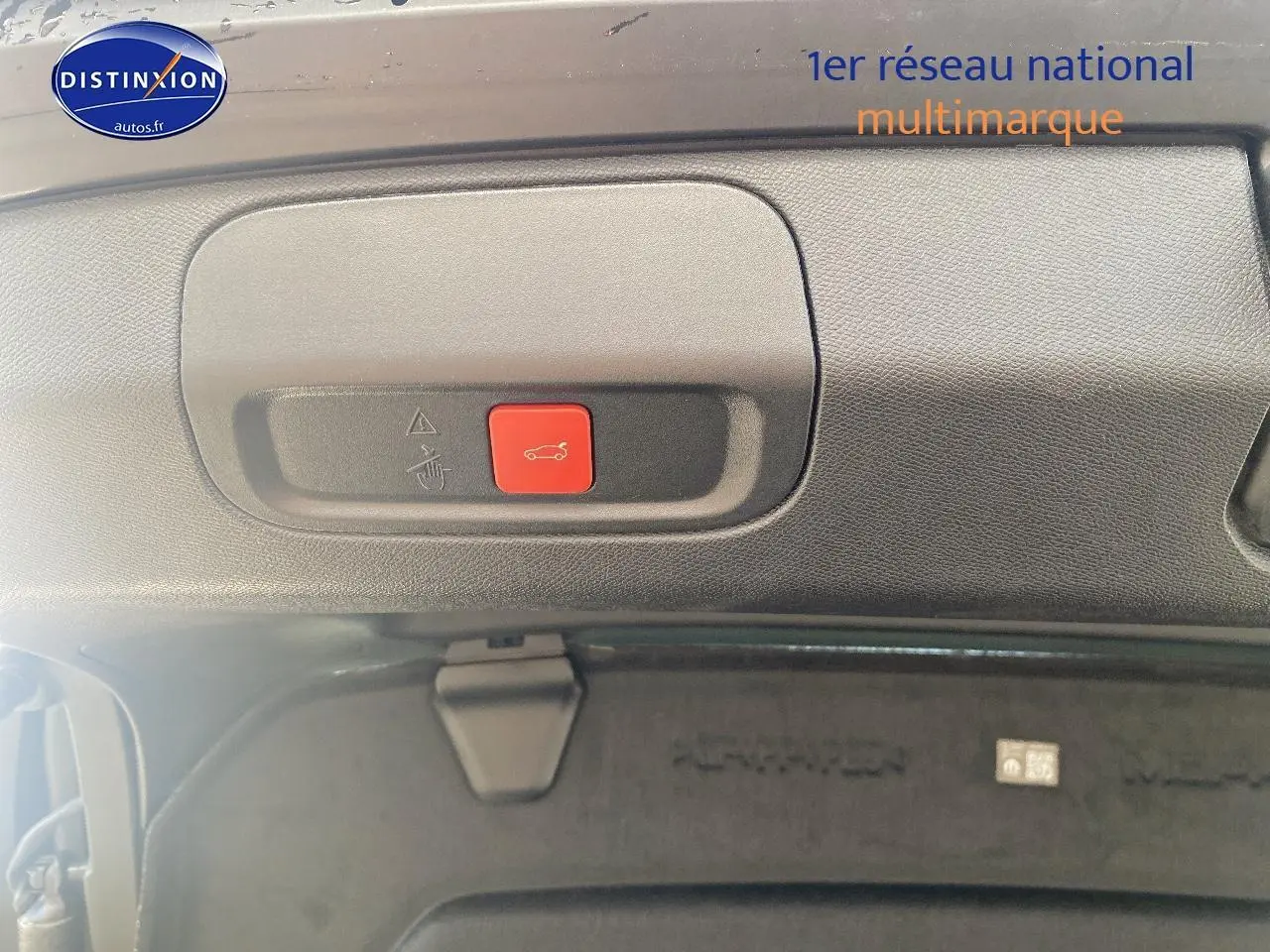 Bouton rouge d'ouverture électrique du coffre visible en gros plan sur la partie intérieure du hayon noir du Peugeot 408 Hybrid 145 GT.