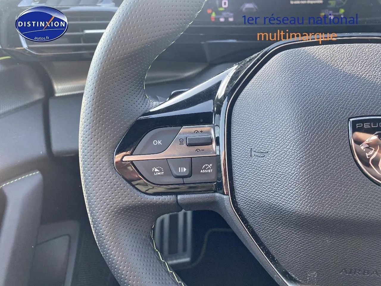 Gros plan sur le volant cuir noir perforé de la Peugeot 408 Hybrid 145 GT avec commandes intégrées côté gauche.