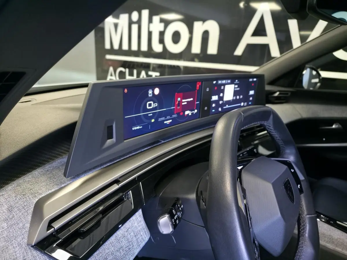 Vue intérieure du tableau de bord du Peugeot 3008 blanc 2025, avec volant compact cuir et double écran HD panoramique.