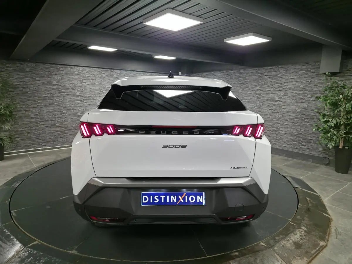 Vue arrière d’un Peugeot 3008 blanc hybride 2025 avec feux arrière LED 3 griffes et bandeau noir laqué.
