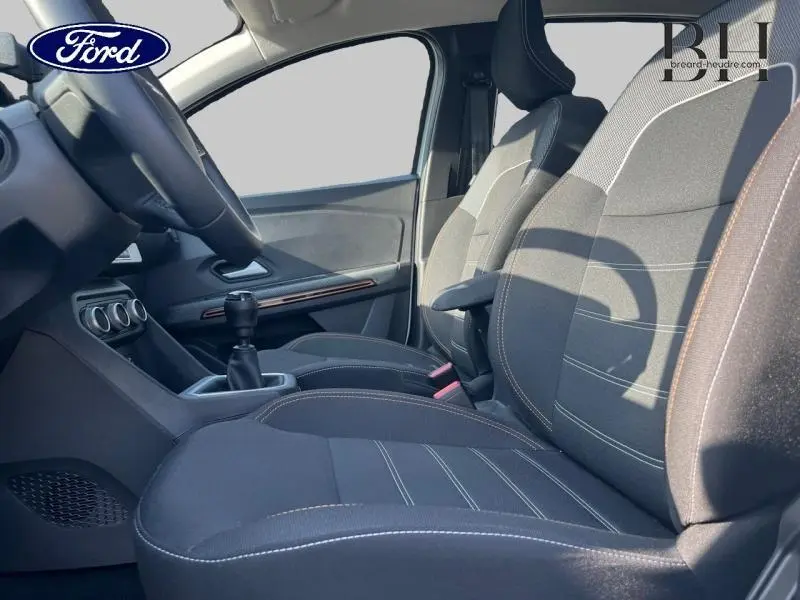 Vue intérieure côté gauche montrant les sièges avant noirs et la console centrale avec levier de vitesse manuel.