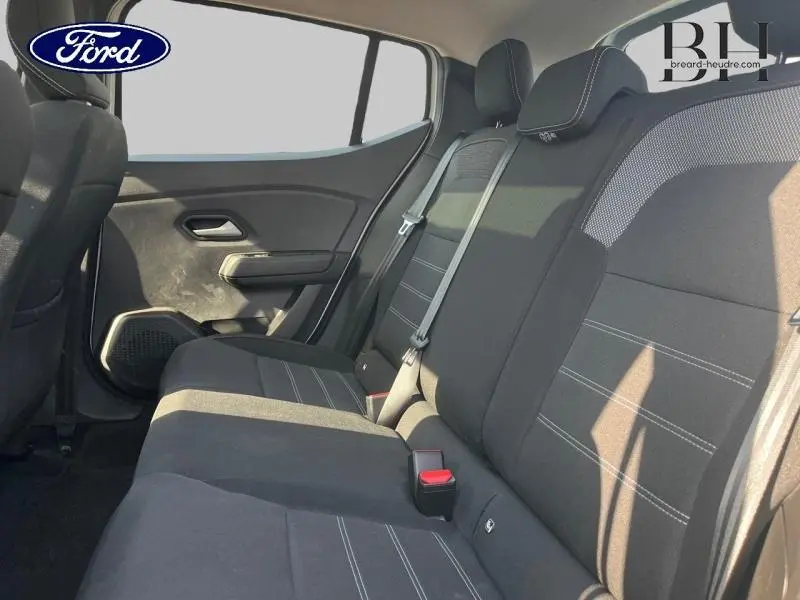 Vue intérieure de la banquette arrière côté droit d'une Dacia Sandero 2023 avec sièges noirs et ceintures grises.