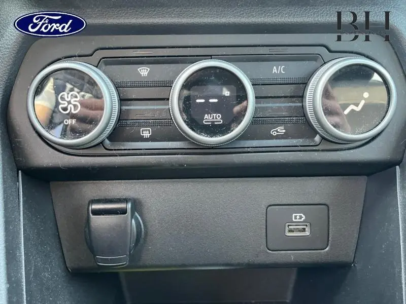 Panneau de commande de climatisation automatique avec trois molettes, prise USB et prise 12V, intérieur noir.