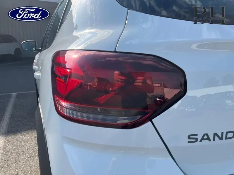 Gros plan sur le feu arrière droit blanc d’une Dacia Sandero 2023 avec attelage, vue arrière côté droit.