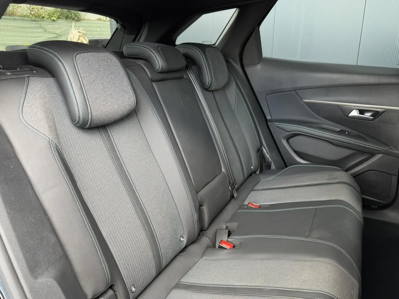 Vue latérale droite de la banquette arrière en tissu et cuir noir avec surpiqûres contrastées du Peugeot 3008 2024.