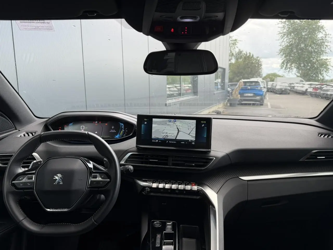 Vue intérieure avant du Peugeot 3008 Plug-in Hybrid 2024, tableau de bord noir avec écran tactile central et volant compact.