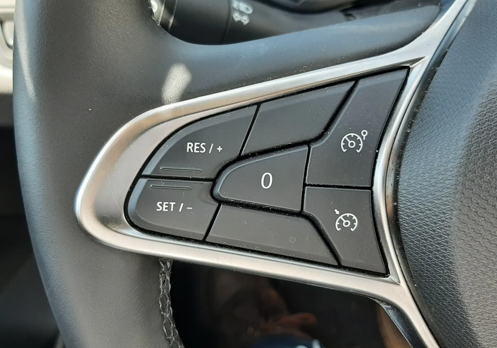 Gros plan sur les commandes de régulateur de vitesse au volant d’une Renault Clio V, intérieur noir.