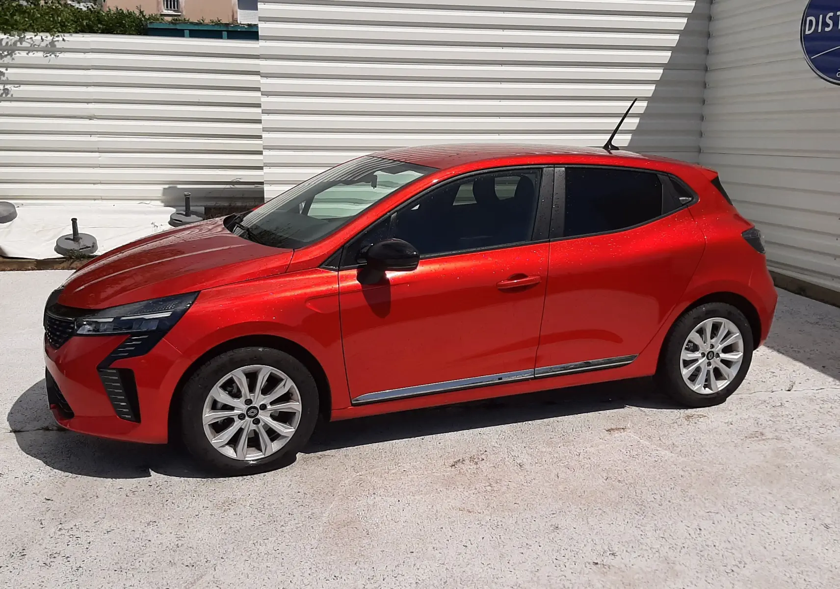 Renault Clio V rouge flamme vue de profil côté gauche, avec jantes alliage et vitres teintées.