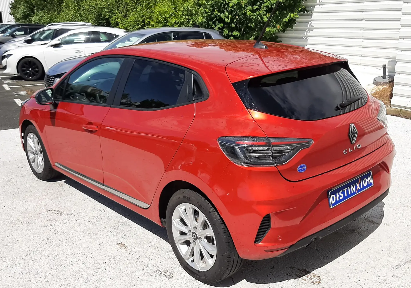 Renault Clio V rouge flamme vue 3/4 arrière droit, avec vitres teintées et feux arrière modernes.