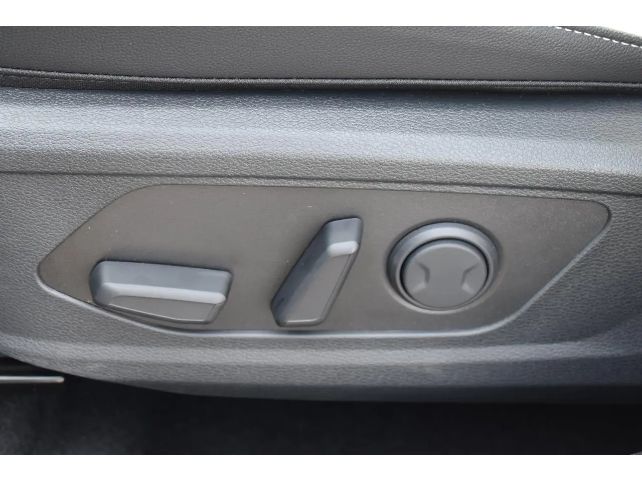 Gros plan sur les commandes de réglage électrique du siège avant gauche du Kia Sportage Hybride gris Loup 2026.