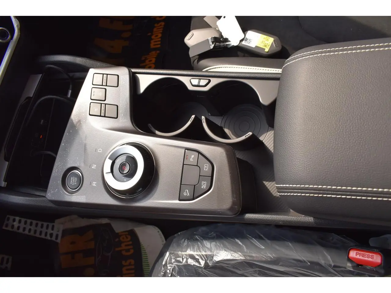 Gros plan sur la console centrale noire avec molette de sélection et porte-gobelets du Kia Sportage Hybride 2026.