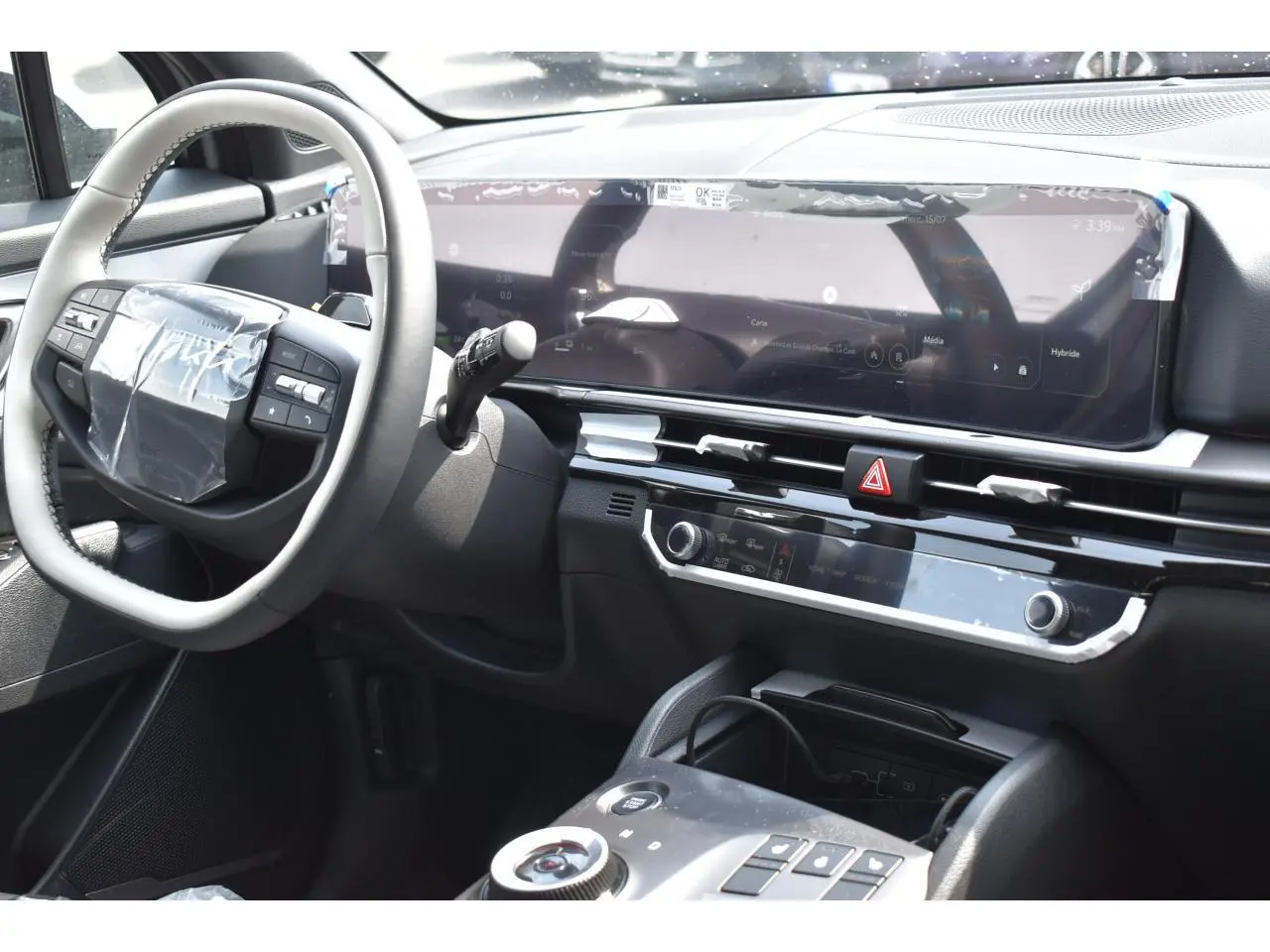 Vue intérieure côté conducteur du tableau de bord du Kia Sportage hybride 2026 avec écran digital panoramique et volant multifonction.
