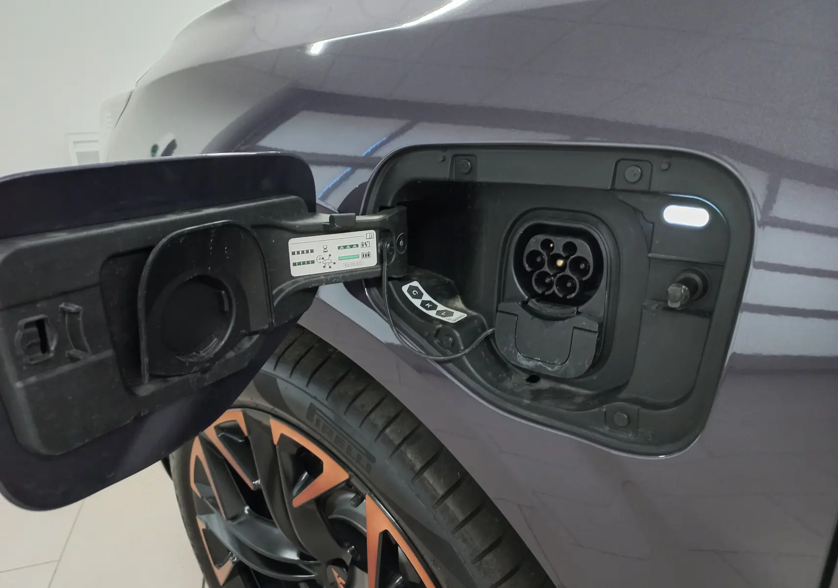 Gros plan sur la trappe de recharge côté gauche du CUPRA Terramar violet intersidéral avec jante 20'' cuivrée visible.