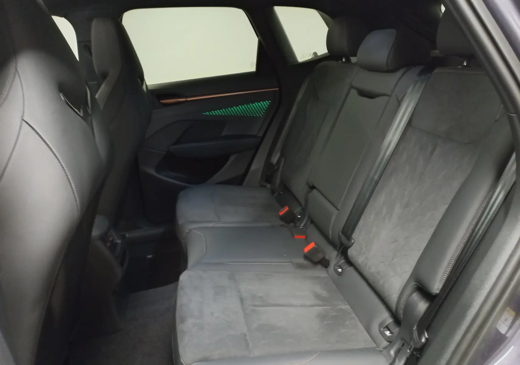 Vue latérale intérieure des sièges arrière en cuir noir du CUPRA TERRAMAR 2025 avec éclairage d'ambiance vert sur la porte.