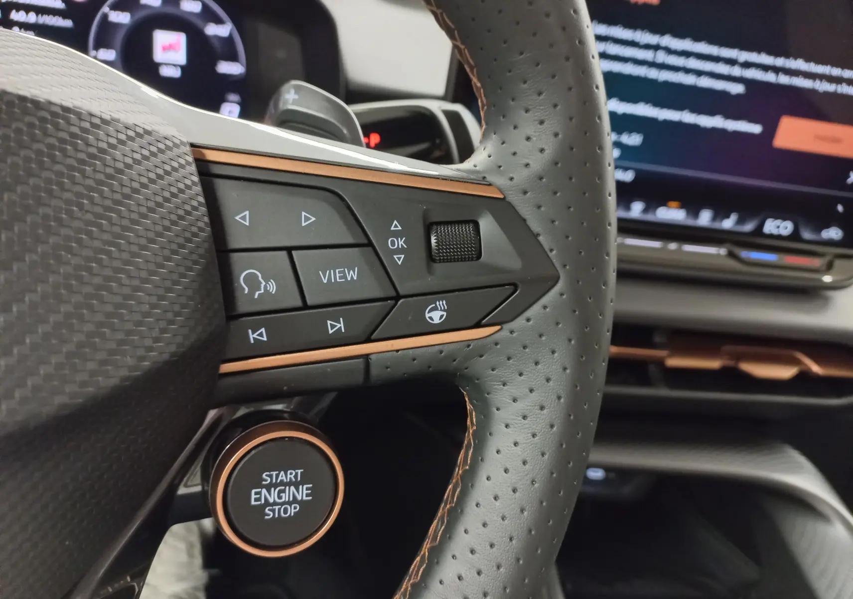 Gros plan sur le volant perforé noir avec surpiqûres cuivrées et bouton start/stop du CUPRA Terramar 2025.