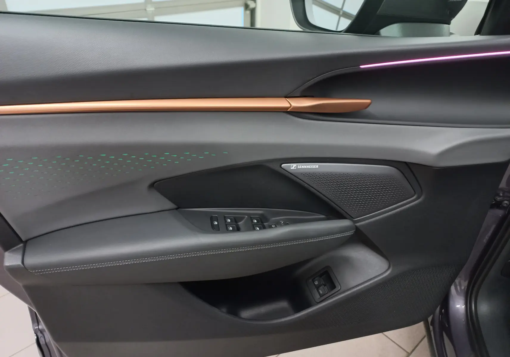 Vue rapprochée de la porte côté conducteur du CUPRA TERRAMAR violet intersidéral, avec haut-parleur Sennheiser et bande cuivrée.