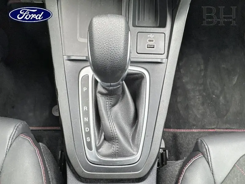 Le levier de vitesse automatique noir du Ford Puma 2025 avec coutures rouges sur les sièges sport en suédine.