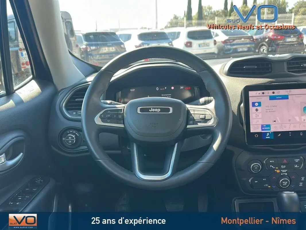 Vue intérieure centrée sur le volant Jeep noir du Renegade 2024 avec écran tactile et commandes au volant visibles.