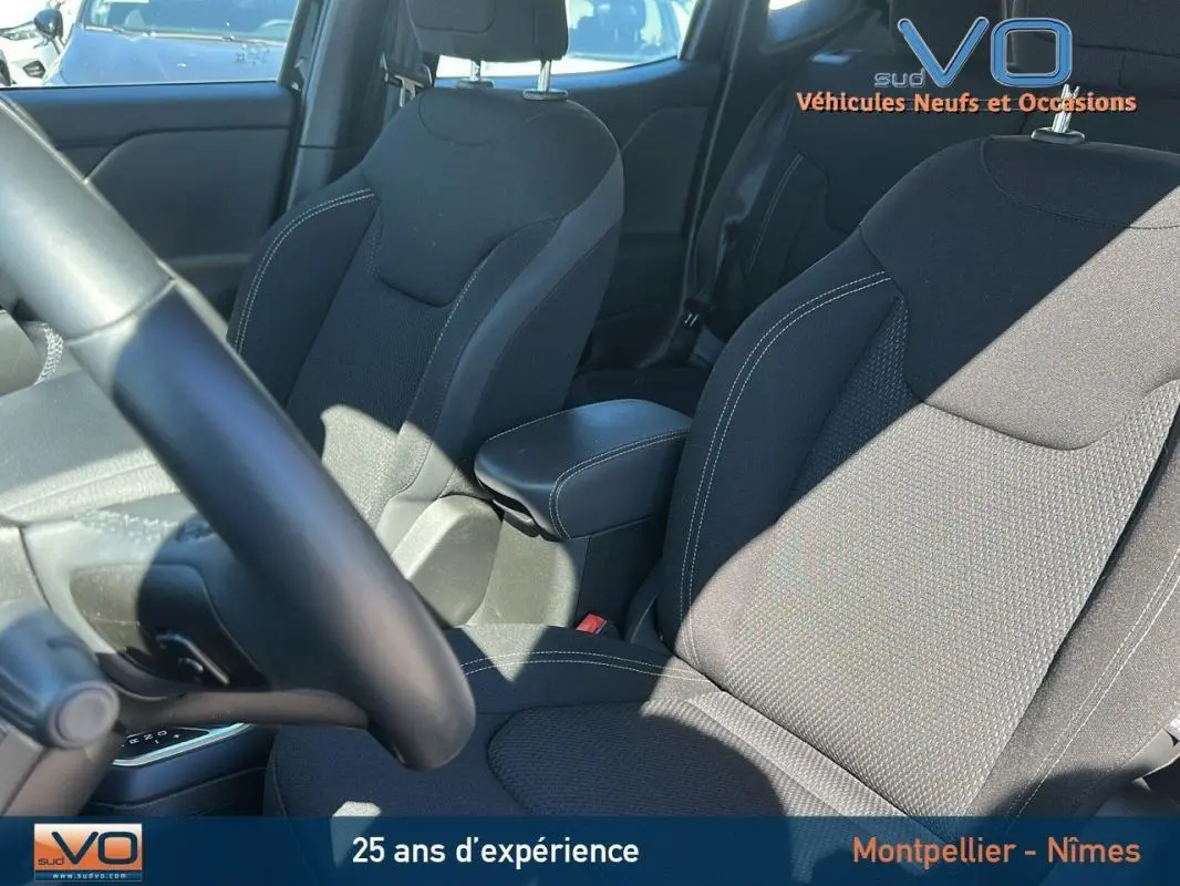 Intérieur du Jeep Renegade 2024 noir, vue sur sièges avant avec accoudoir central et volant partiellement visible.