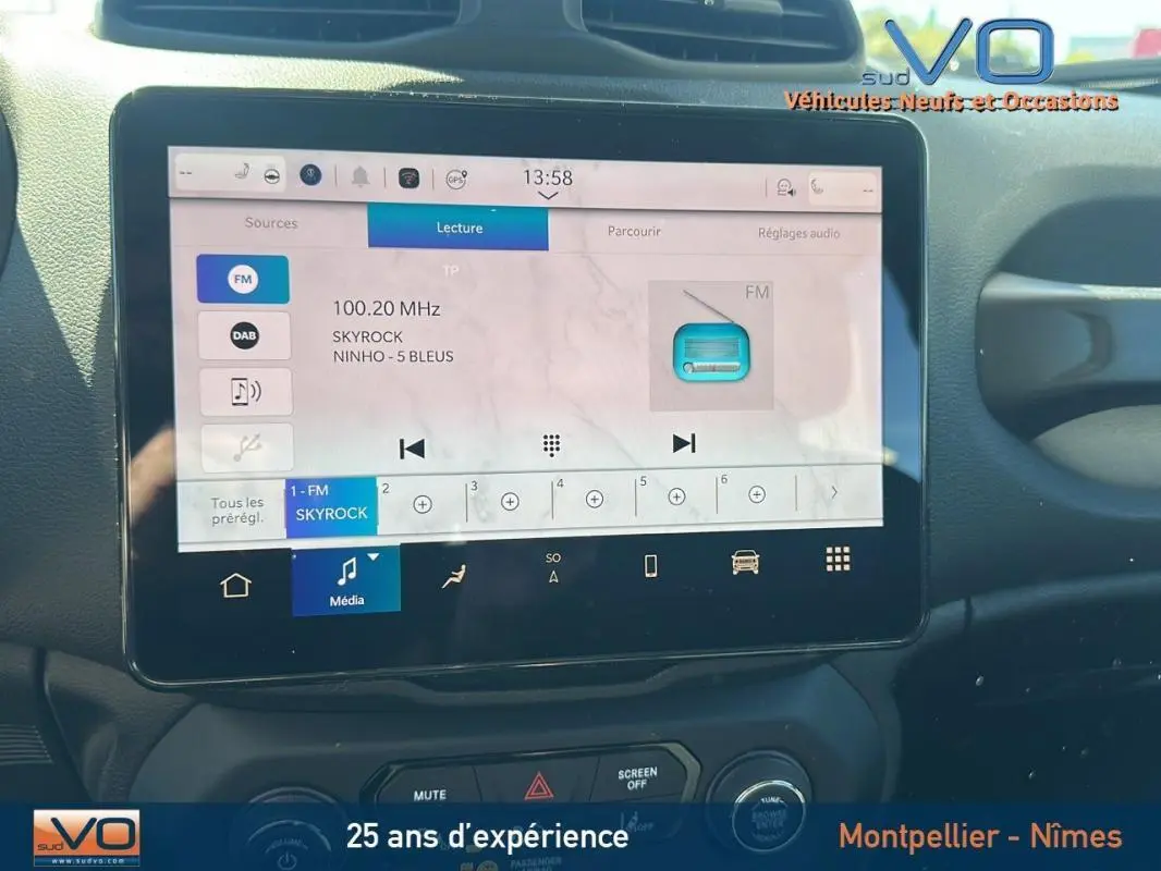 Écran tactile central du Jeep Renegade 2024 affichant la radio FM Skyrock, avec commandes et tableau de bord noirs.