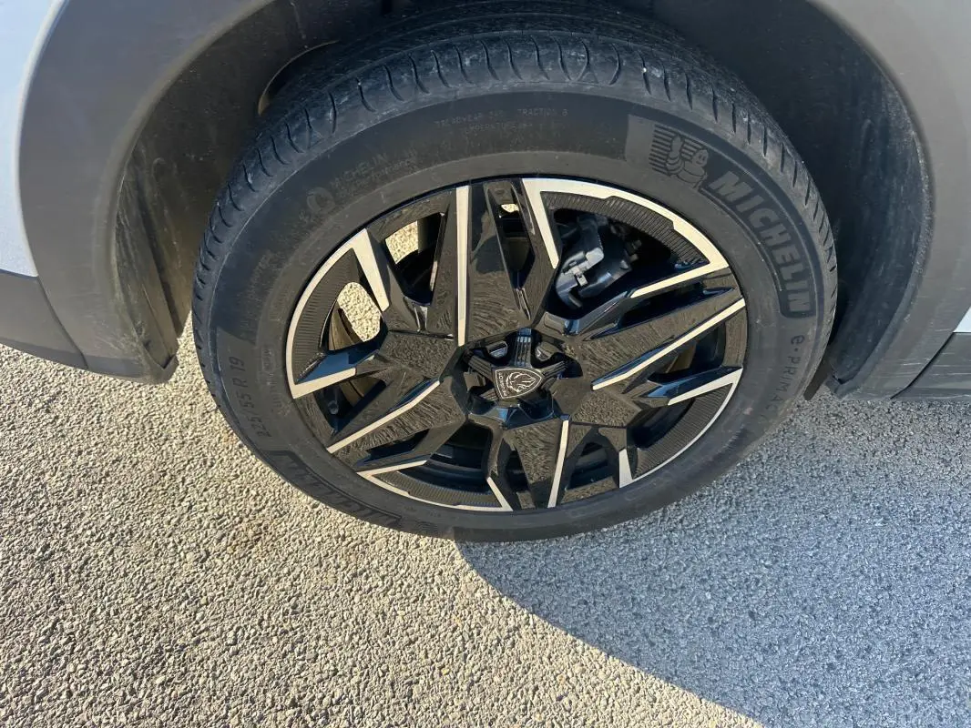 Gros plan sur la jante alliage 19 pouces noire et argentée du Peugeot 3008 Hybrid blanc, côté avant droit.