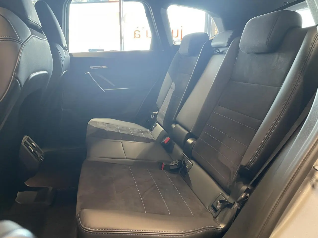 Vue latérale intérieure des sièges arrière en Alcantara noir avec surpiqûres bleues du BMW X1 xDrive20d 2024 Spacesilber Metallic.