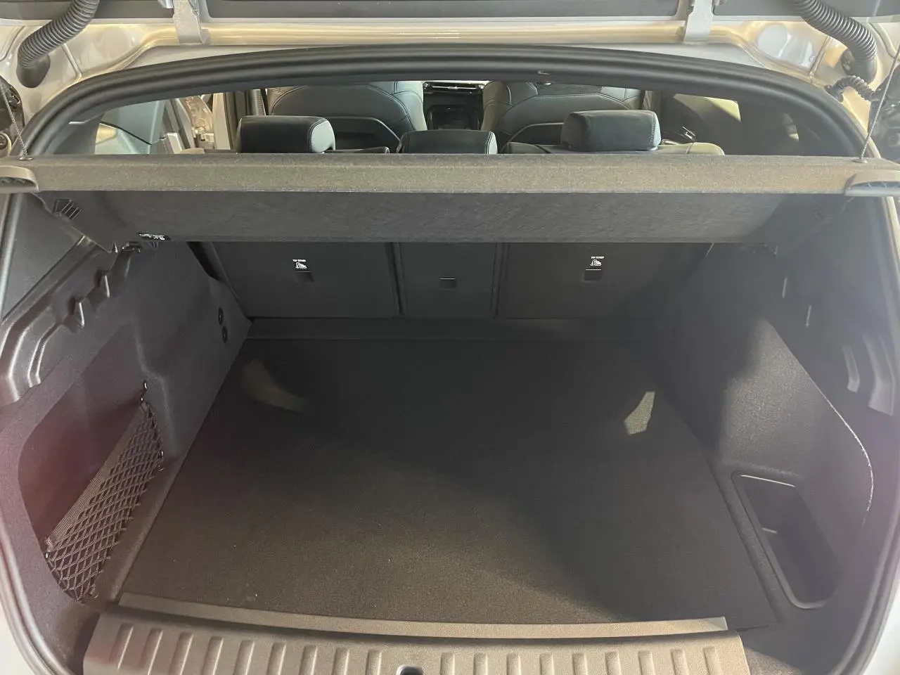 Coffre spacieux ouvert d’un BMW X1 xDrive 20d 2024 en couleur Spacesilber Metallic, avec filet de rangement latéral.