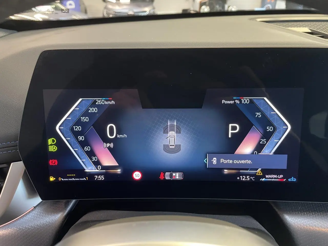 Tableau de bord numérique du BMW X1 xDrive 20d 2024 affichant vitesse, puissance et alerte porte ouverte.