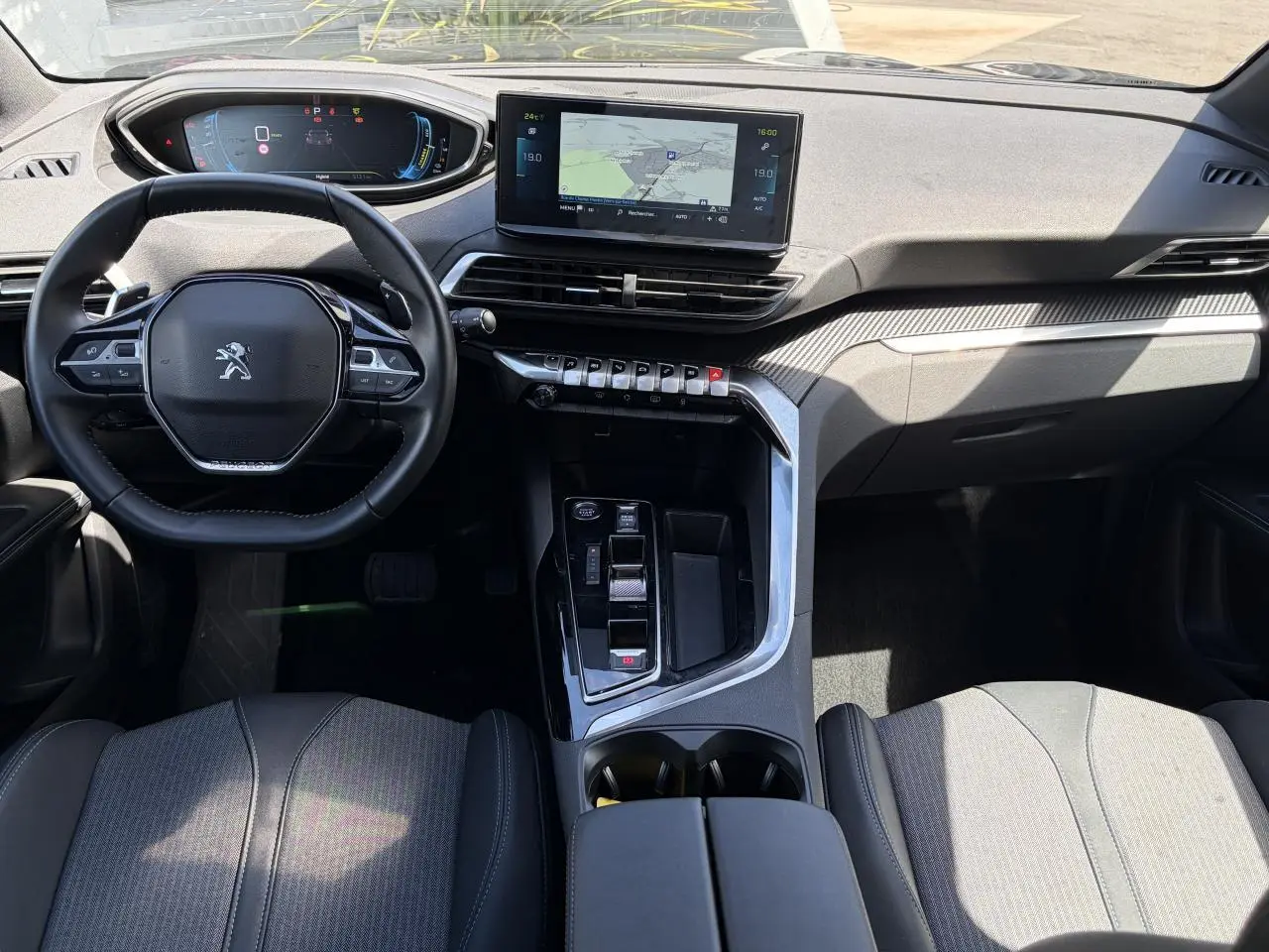 Vue intérieure avant du Peugeot 3008 Plug-in Hybrid 2024, volant compact, écran tactile central et console moderne noire.